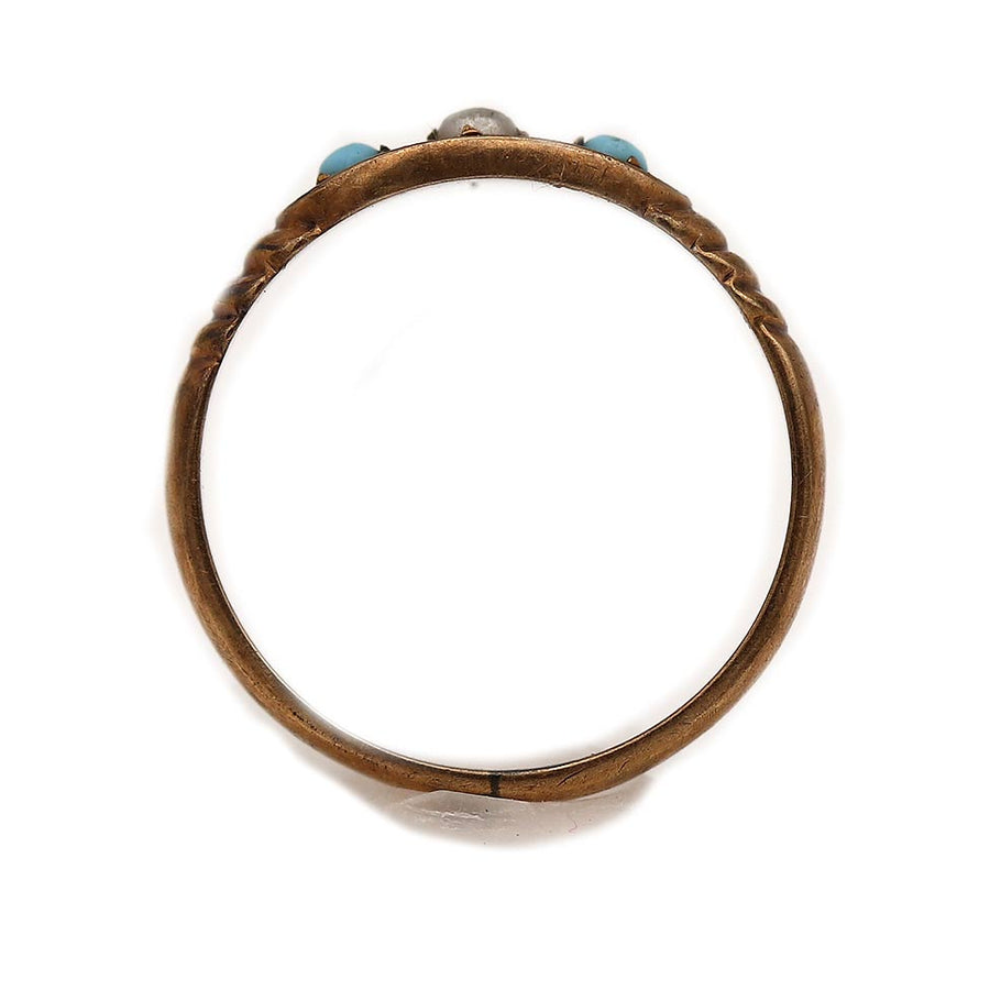 Close-up view of a dainty Victorian turquoise and pearl starburst wedding ring in 10K rose gold