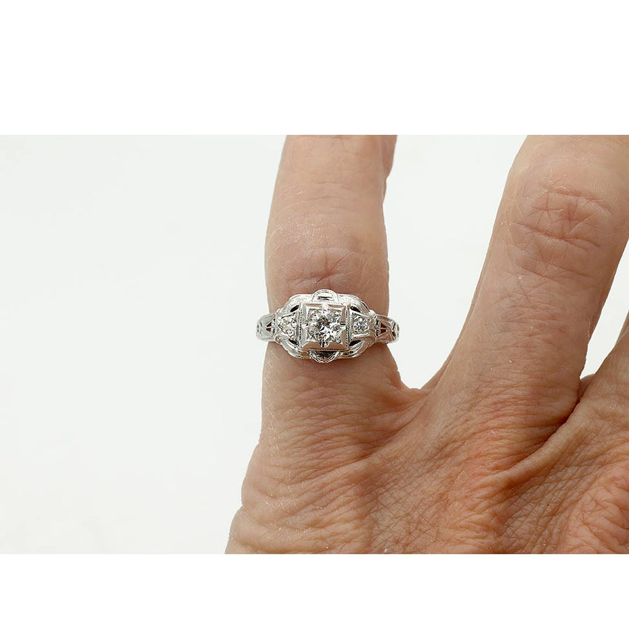 Art Deco three stone engagement ring in 14K white gold featuring an old European cut diamond in a geometric square frame with diamond side stones on hand.
