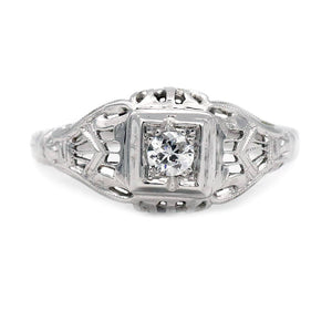 Art Deco old European cut diamond solitaire engagement ring in 18K white gold featuring a geometric square frame, open metalwork, and milgrain engraving.