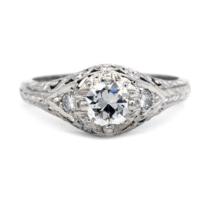 Estate Art Deco style platinum engagement ring featuring a GIA certified .55 carat old European cut diamond with diamond side stones, milgrain, and filigree detail.
